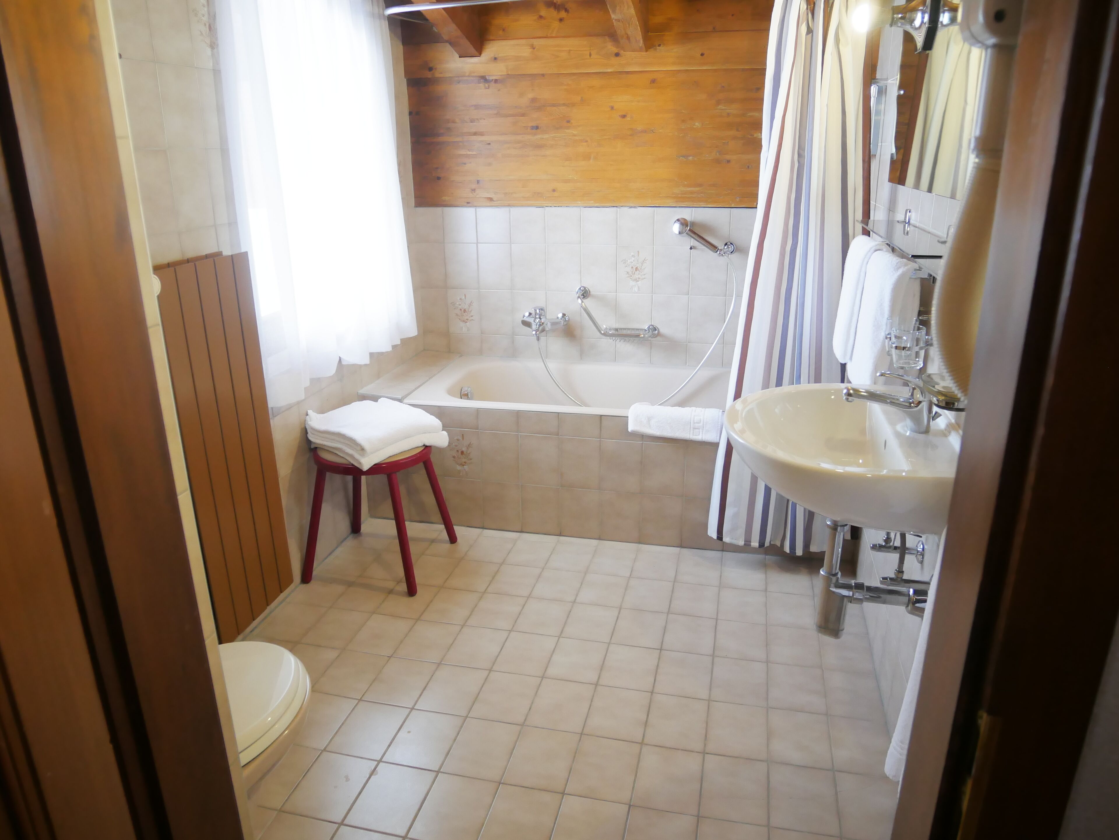 A bathroom with a wooden ceiling, a bathtub, a sink, and a toilet.