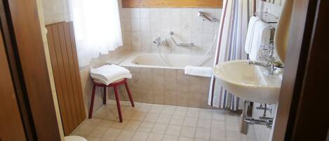 Une salle de bain avec un plafond en bois, une baignoire, un lavabo et des toilettes.