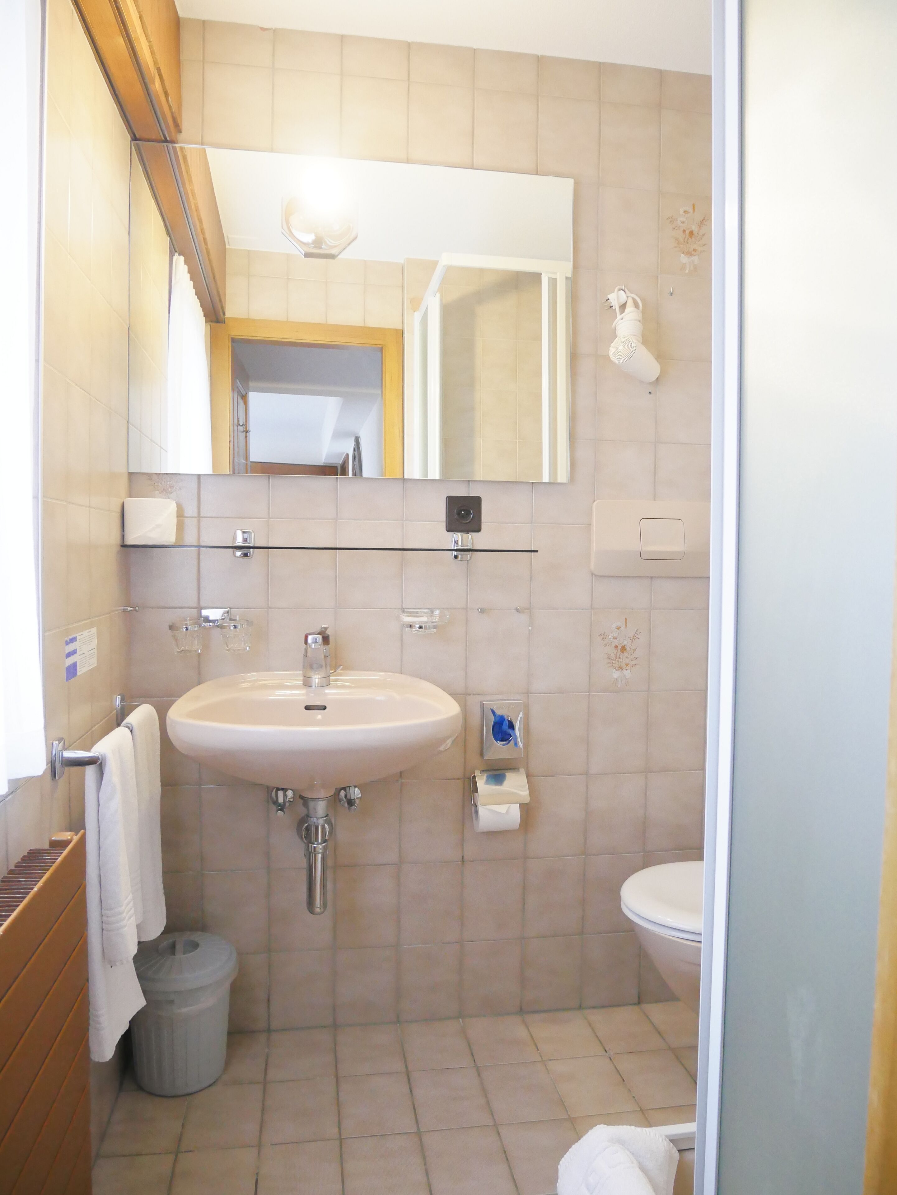 A bathroom with a sink, mirror, toilet, and shower.