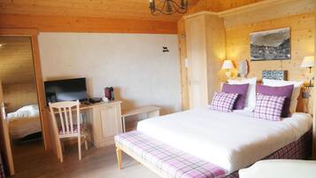A wooden room with a bed, a desk, and a television.