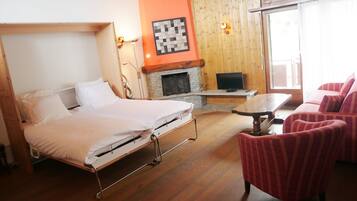 Une chambre comprenant un lit, une cheminée, un téléviseur et un coin salon avec des fauteuils.