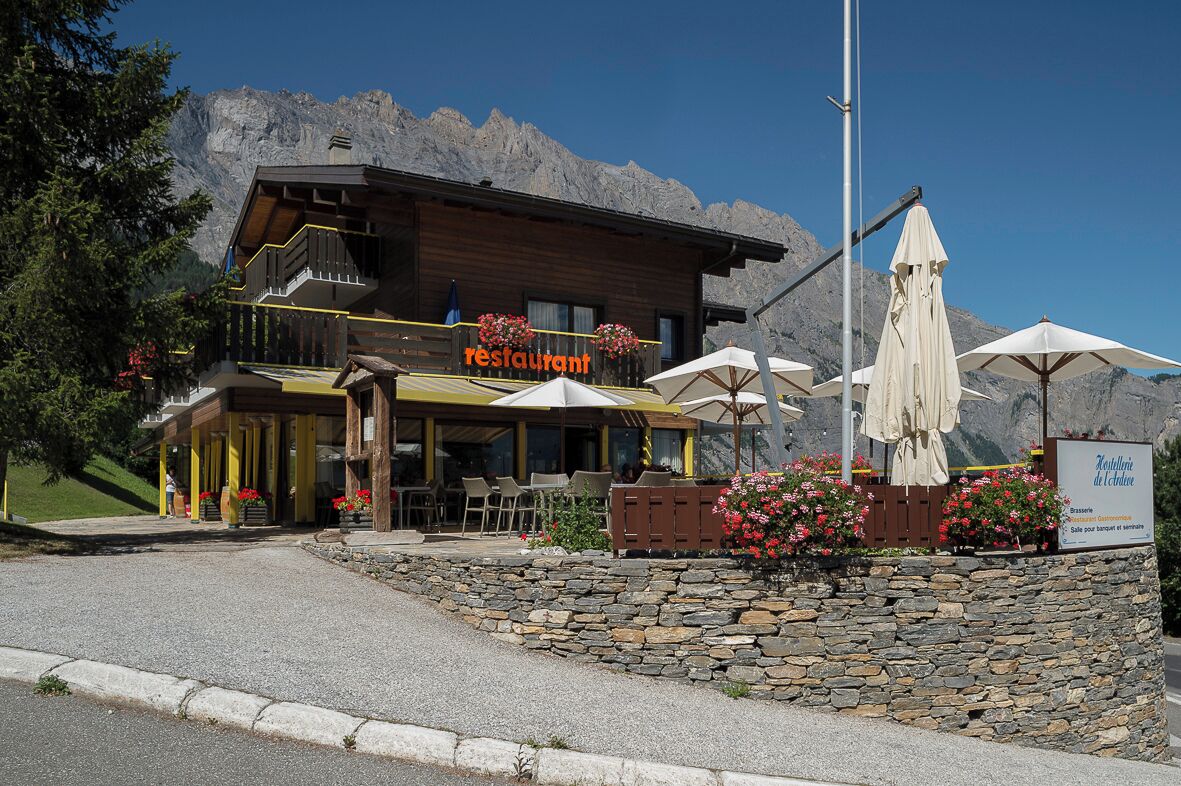 Un restaurante con terraza, paredes de piedra y vistas a la montaña.
