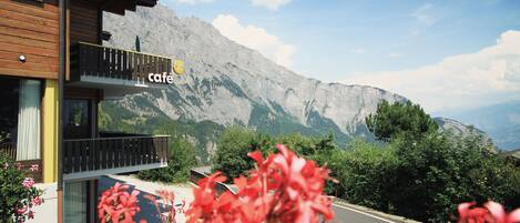 Hotel con vistas a la montaña, balcón y cartel de café.