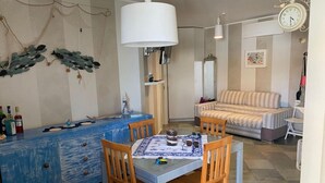 Una habitación acogedora con una mesa de comedor, sillas, un sofá, un reloj y un adorno en la pared.