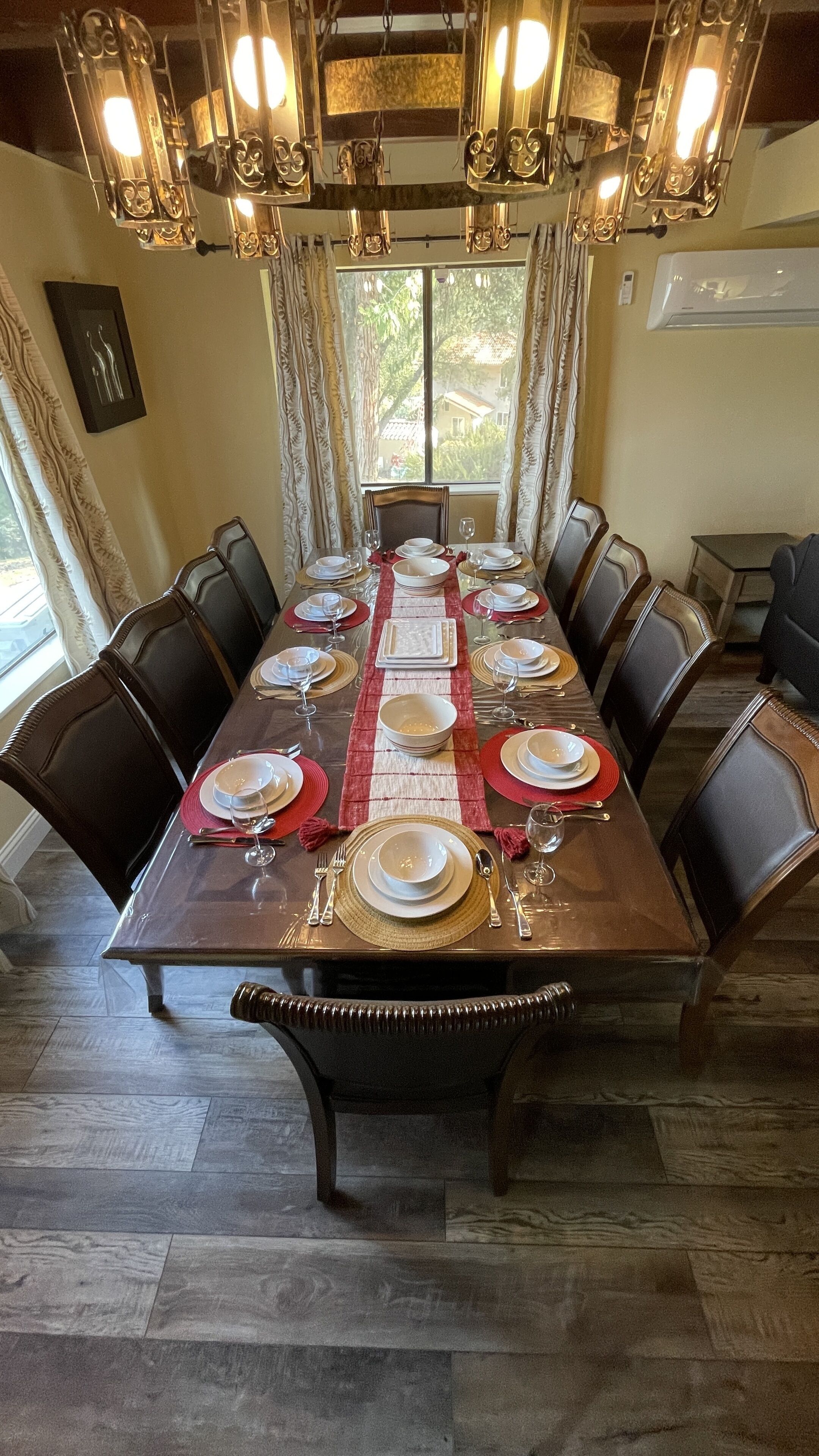 A dining room with a long table set for a meal, surrounded by chairs.