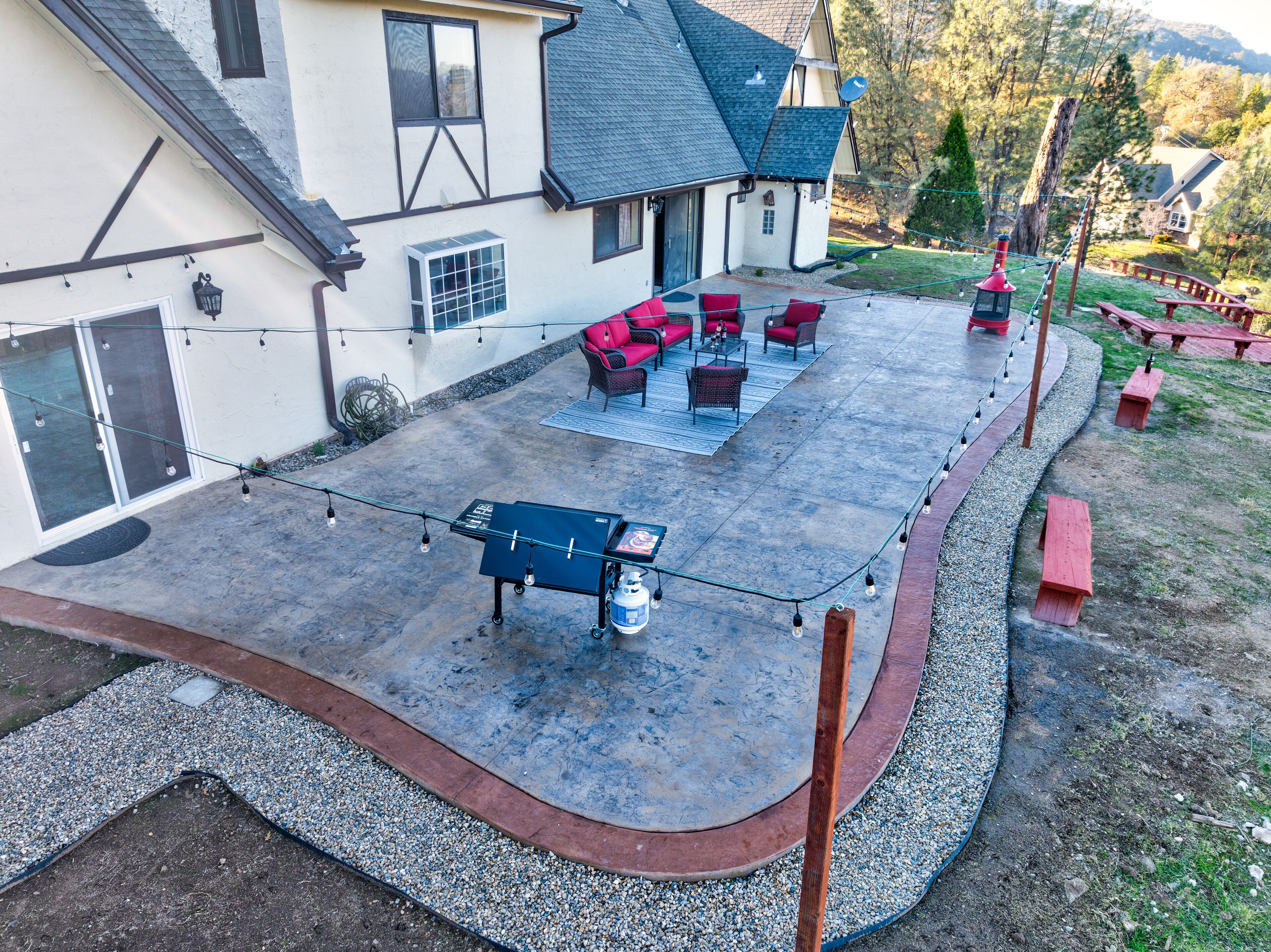 A covered patio area with outdoor seating, a pool table, and a barbecue grill.