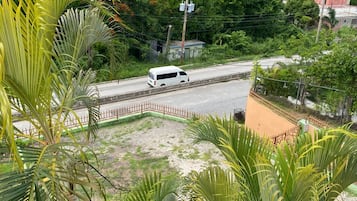 A white van on a road with a red fence and greenery in the foreground.