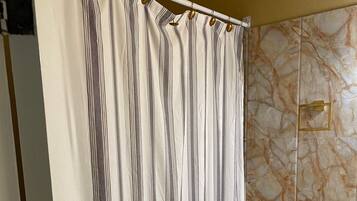 A bathroom with a striped shower curtain, a toilet, and marble-patterned walls.