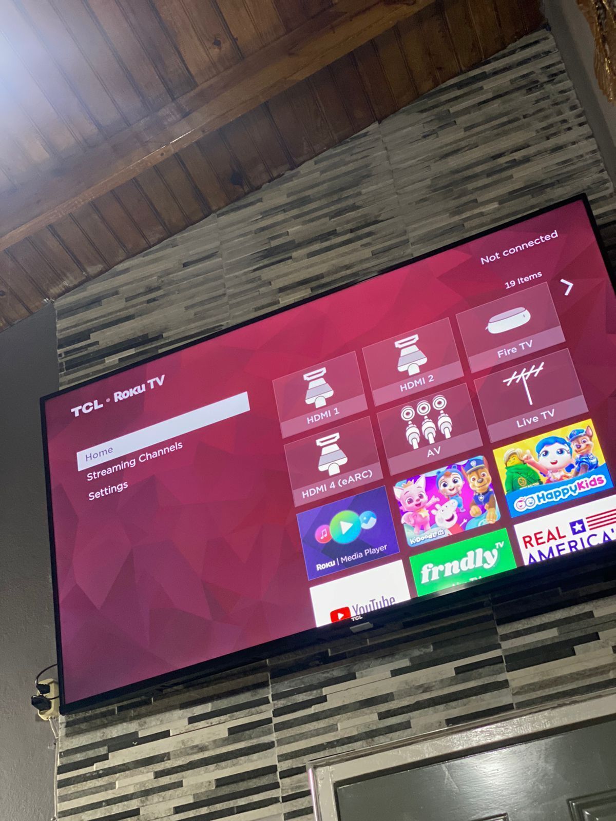 A TCL Roku TV displaying various streaming channels and settings.