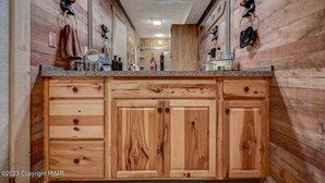 Un baño de madera con un espejo grande, armarios de madera y anillas para toallas en las paredes.