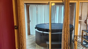 Una habitación con puerta de cristal corredera que da a un balcón, suelo de madera y una alfombra pequeña.