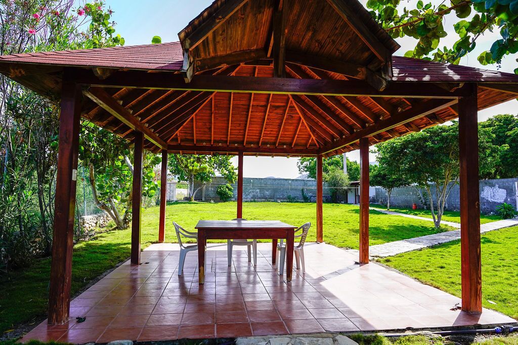 A wooden gazebo with a tiled patio, a table, and chairs.