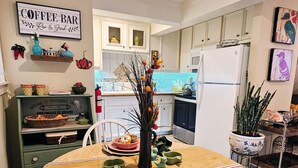 A dining area with a table set for two, a coffee bar sign, and kitchen cabinets in the background.