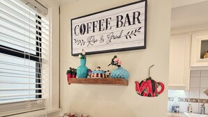 A kitchen with a coffee bar sign, various kitchenware, and a fire extinguisher.