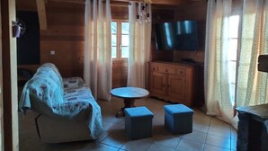 Una habitación acogedora de estilo cabaña con un sofá, una mesita y dos otomanas.