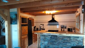 Una cocina moderna con una isla de piedra, armarios de madera y sillas azules.