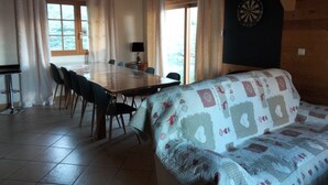 Una habitación acogedora con una mesa y sillas de madera, un sofá estampado y un dardo en la pared.