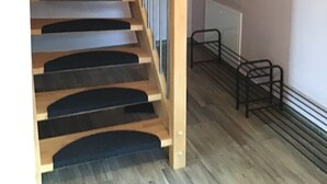 En trætrap med gelænder, en fastmonteret radiator og en lille hylde med pynt.