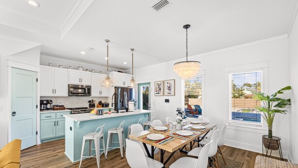 A modern kitchen with white cabinets, a central island, and pendant lighting. - Heated Pool, Pickeball, Beach House (Panama City Beach)