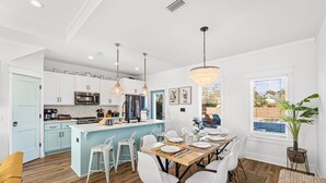 A modern kitchen with white cabinets, a central island, and pendant lighting.