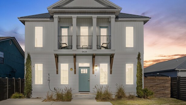 A two-story house with a front porch, a green door, and a number "5426" on the front.