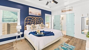 A bedroom with a bed, a ceiling fan, a window with blinds, and a door. - Heated Pool, Pickeball, Beach House (Panama City Beach)