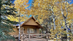 A log cabin with a wooden deck and a stone foundation. - Cozy Utah Cabin (Kamas)
