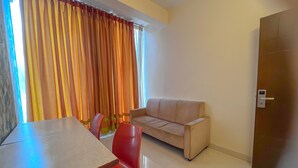 A room with a dining table, red chairs, a beige sofa, and a wooden door. - Hotel Willow Tree (Bengaluru)