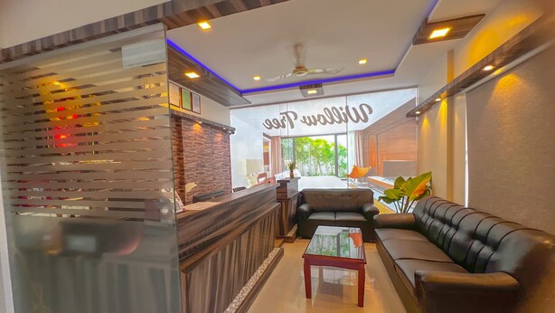 A modern hotel lobby with a reception desk, a sofa, and a coffee table. - Hotel Willow Tree (Bengaluru)