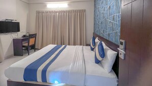 A hotel room with a bed, a desk, a television, and a ceiling fan. - Hotel Willow Tree (Bengaluru)