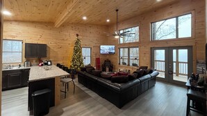 Un amplio salón con un gran techo de madera, una chimenea acogedora y un árbol de Navidad.