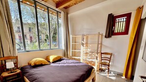 A room with a bed, a chair, a desk, and a window. - L'atelier du Salagou (Octon)