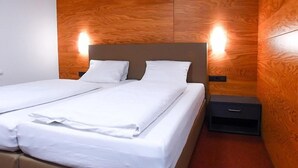 A double bed with white linens, a wooden headboard, and two bedside tables.