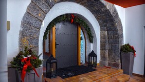 A stone archway leading to a door with a wreath and red ribbon decoration.