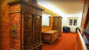 A room with a large wooden cabinet, a small table, and a chair.