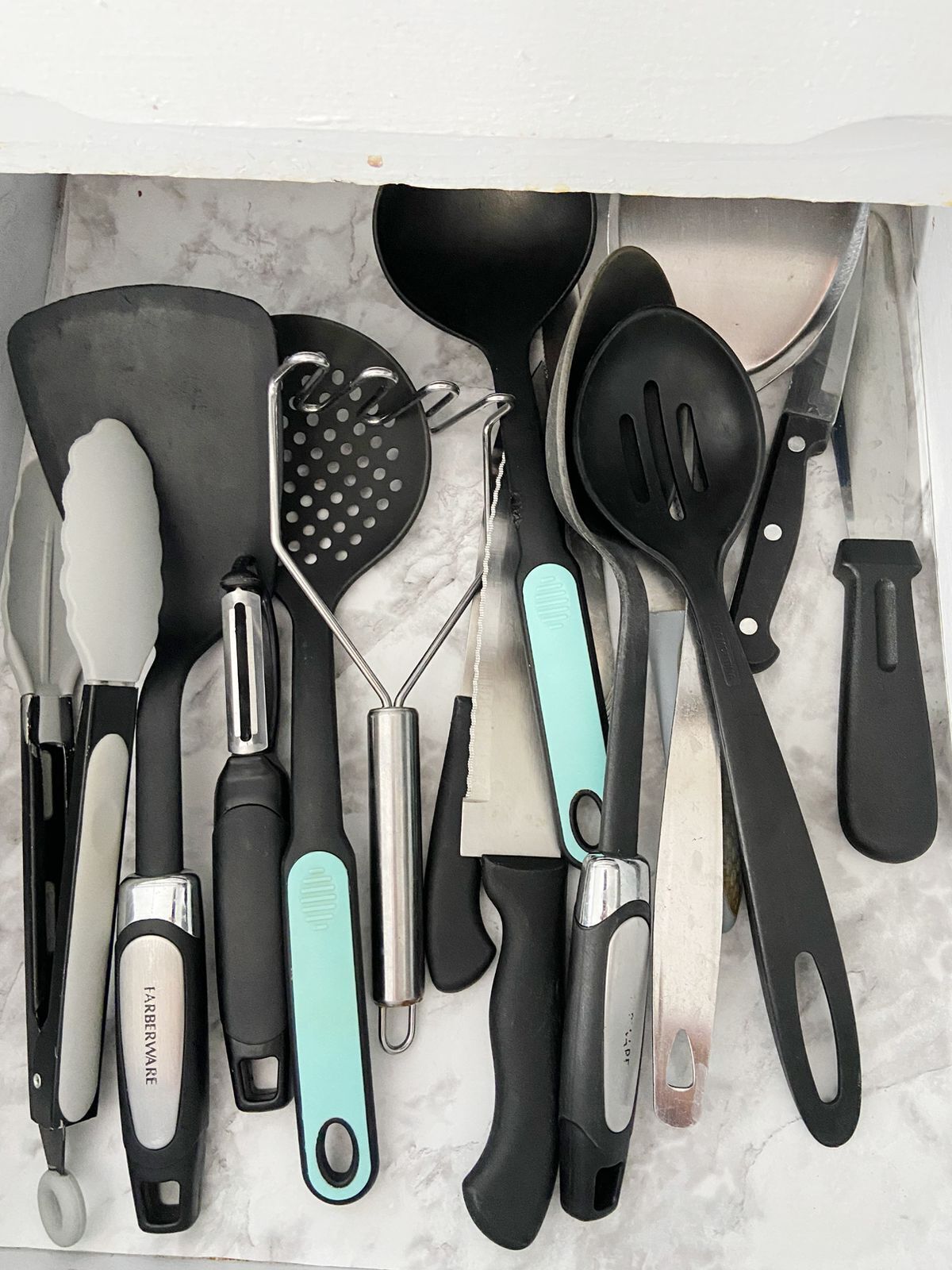 Eine Schublade mit verschiedenen Küchenutensilien, darunter ein Pfannenwender, eine Reibe und ein Messer.