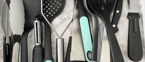 Eine Schublade mit verschiedenen Küchenutensilien, darunter ein Pfannenwender, eine Reibe und ein Messer.