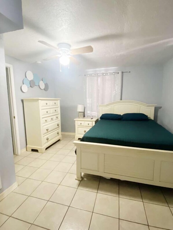 A bedroom with a bed, dresser, nightstand, and a ceiling fan.
