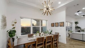 A dining area with a wooden table, chairs, and a modern chandelier. - 2 Luxury Homes | Group Retreats | Games | Fire Pit (Round Rock)