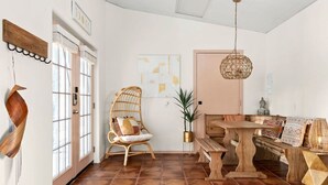 A spacious room with a wooden bench, a wicker chair, and a dining table. - 2 Luxury Homes | Group Retreats | Games | Fire Pit (Round Rock)