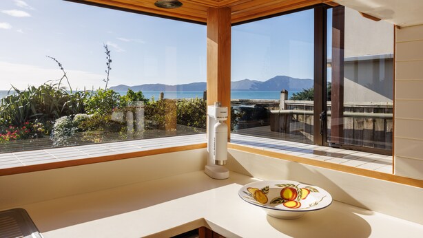 Una cocina con un ventanal que ofrece una vista panorámica de montañas y una masa de agua.