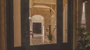 A hallway with a checkered floor, stone walls, and a wooden door. - Maria Rosa Suites (Victoria)