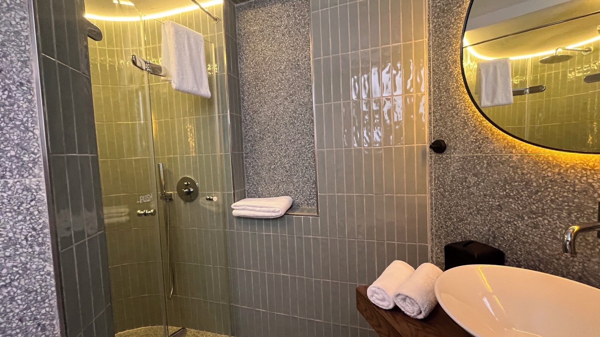 A modern bathroom with a glass-enclosed shower, a sink, and a mirror.
