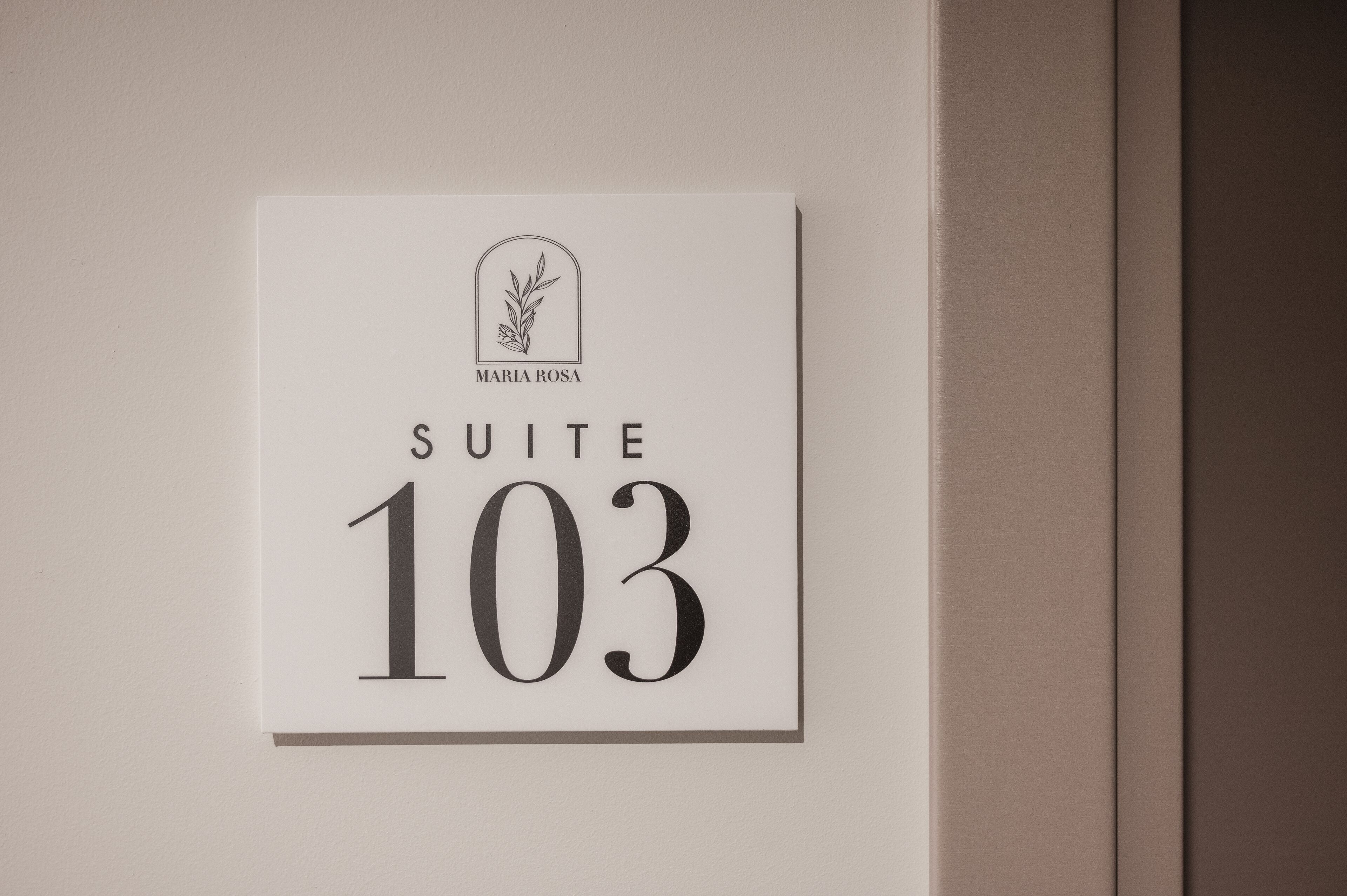 Et skilt med teksten 'SUITE 103' og en logo over.