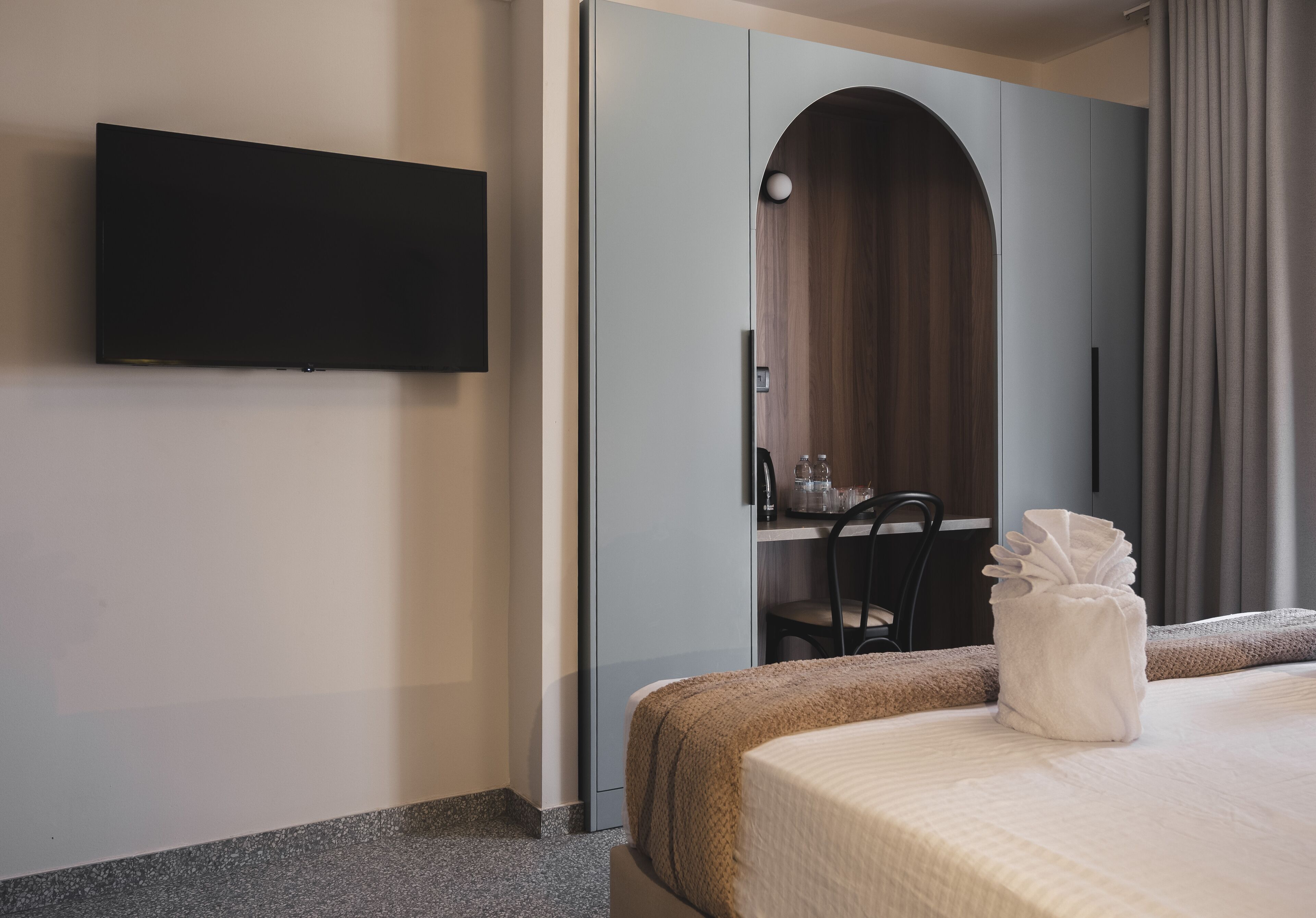 Ein Hotelzimmer mit Bett, Wandfernseher, Schreibtisch mit Stuhl und Badezimmer.