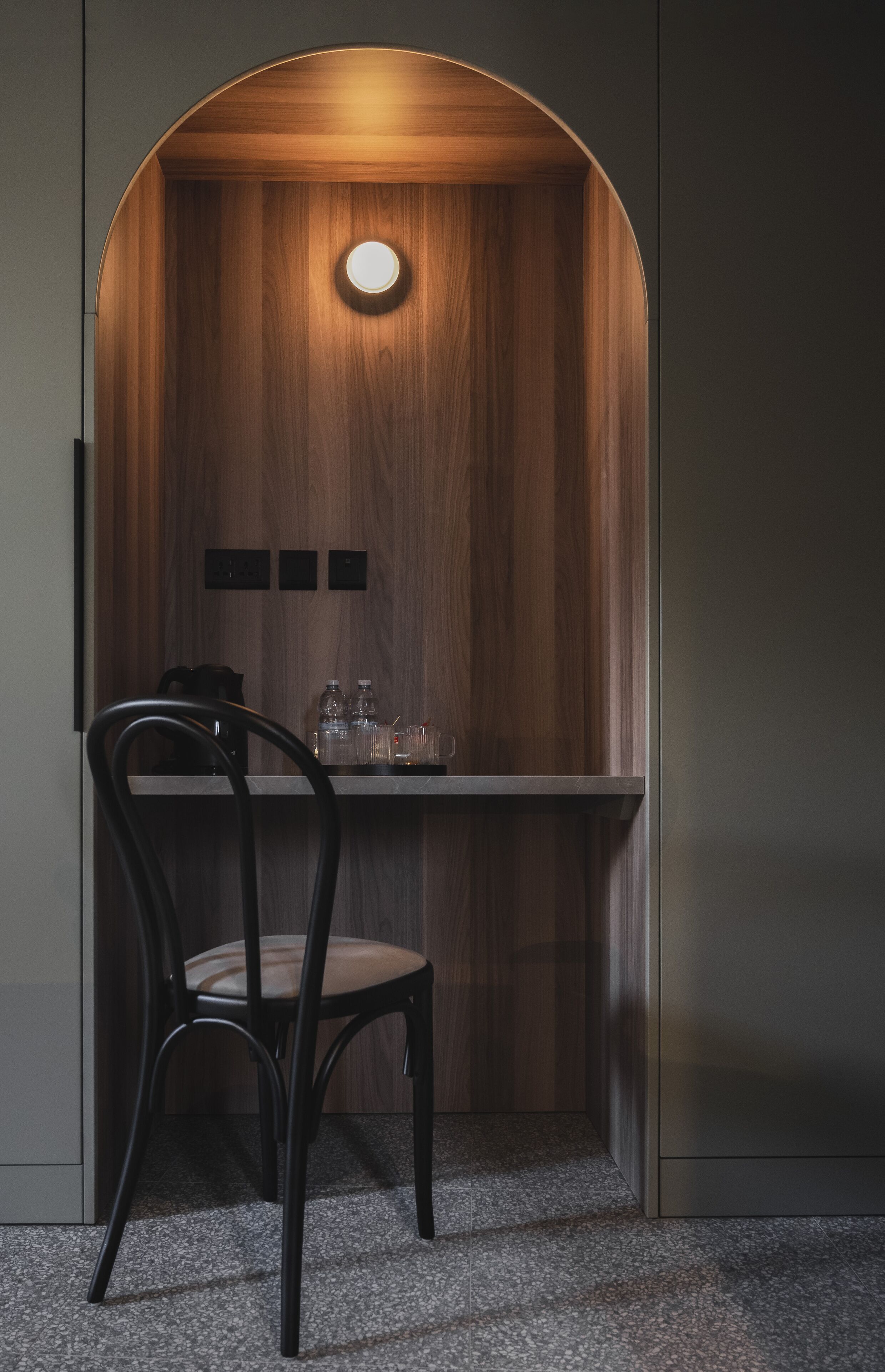 A small, enclosed seating area with a wooden interior, a round light fixture, and a chair.