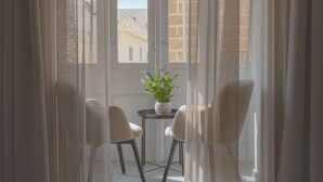 A room with a view through a window, featuring a potted plant on a small table and two chairs. - Maria Rosa Suites (Victoria)