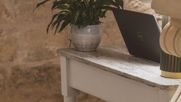 A checkered floor, a white table with a laptop and a potted plant, and a stone wall.