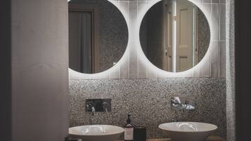 A bathroom with two round mirrors, a wooden vanity, and a bottle of hand soap.