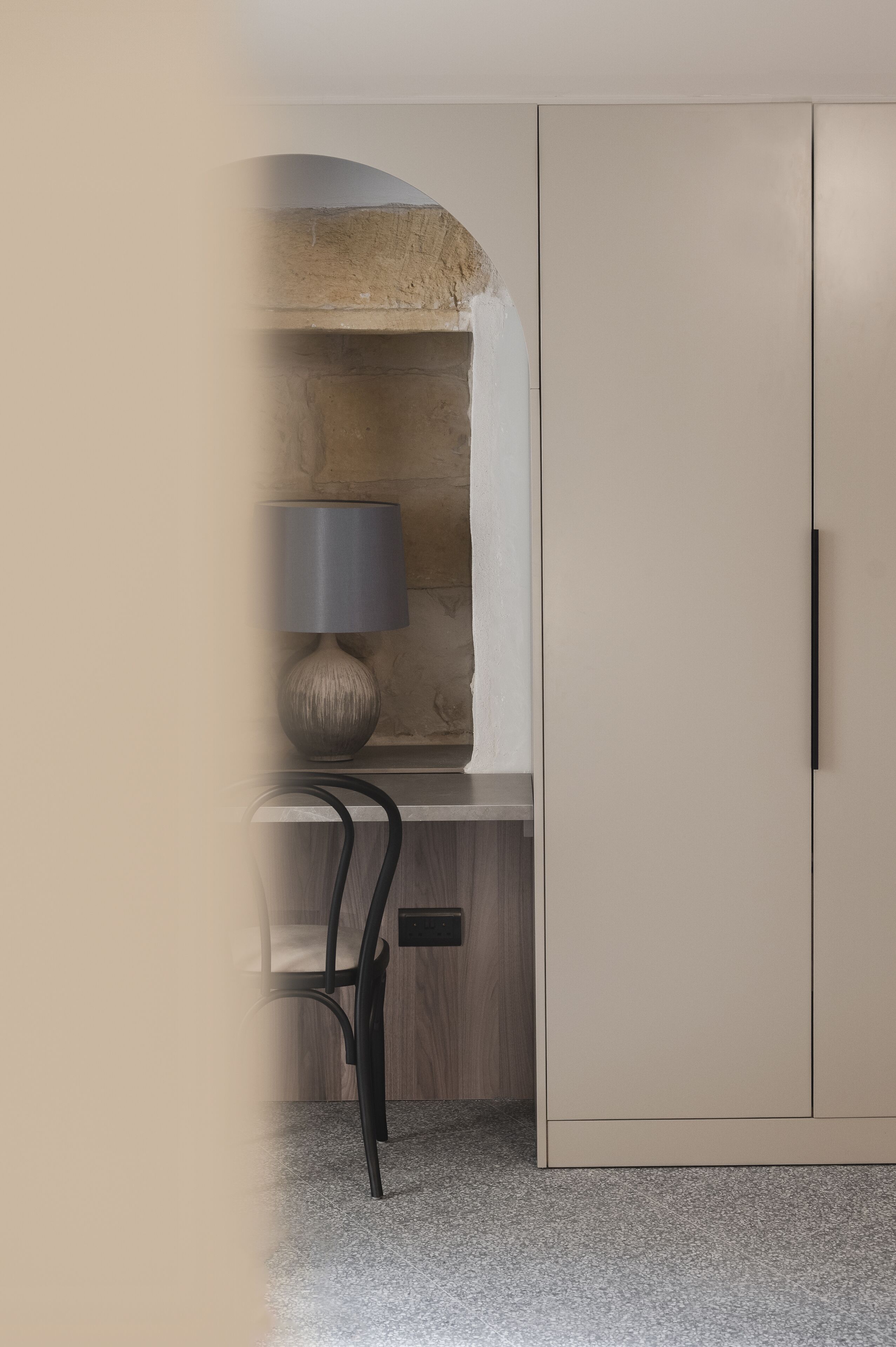 Una habitación moderna con escritorio integrado, una lámpara y un armario.